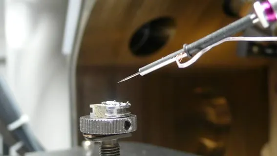 Macro shot of the MSU tip touching a metal rod, showing a tiny bright solder point at the contact.