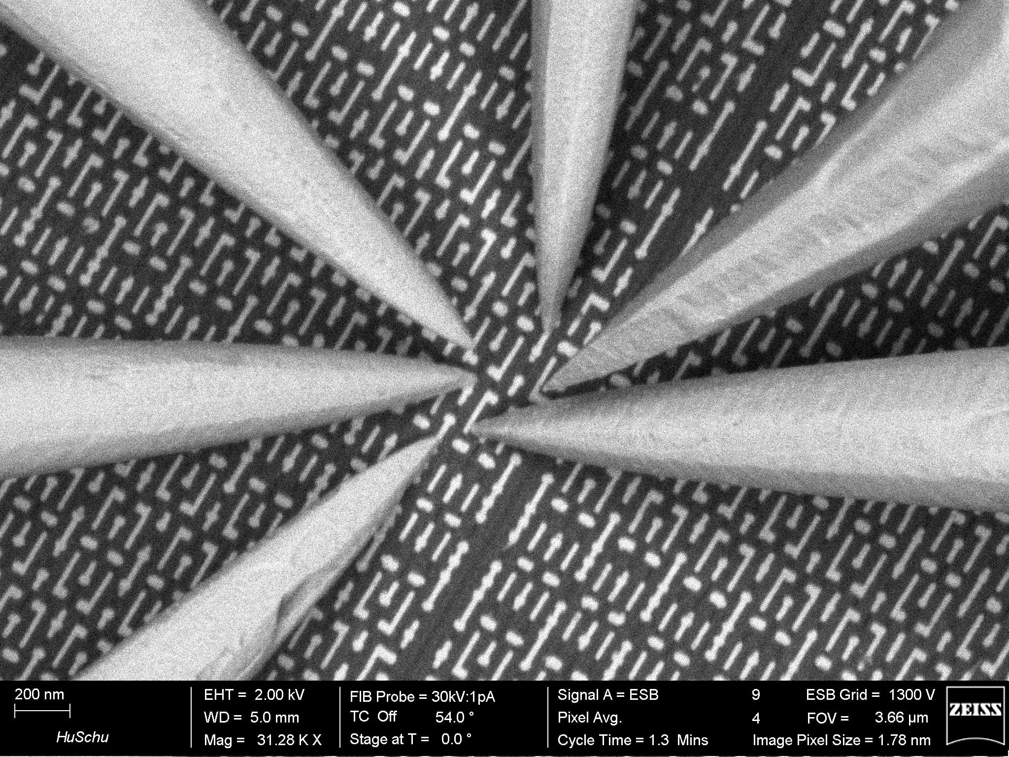 Eight nanoprobe tips converging to a single point on a patterned semiconductor device.