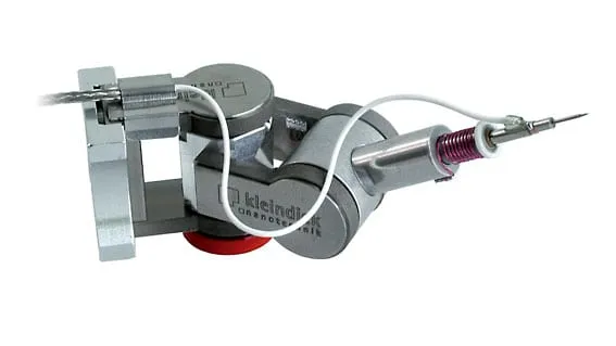 The LCMK-EM low-noise probe-tip holder on a Kleindiek MM3A-EM micromanipulator, with shielded triax cabling running to a fine tungsten probe tip.