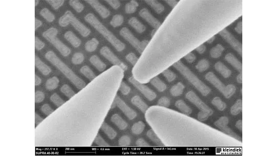SEM image of three probe tips converging on a patterned chip surface, 200 nm scale bar, magnification and imaging parameters overlaid.