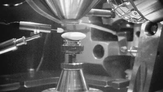 In-chamber view of the MIS-EM pipette tip with a small liquid droplet formed at its point, positioned above the sample stage.