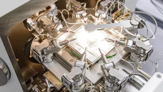 The ProbeWorkstation+ installed inside an SEM chamber with manipulators arranged around the sample stage.