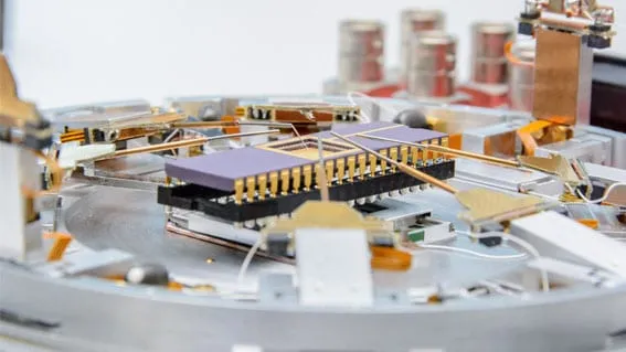 Close-up of a chip carrier and socket assembly mounted on the PS8 platform, probe arms visible in the background.